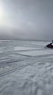 Рыбаки на снегоходах перепрыгивают через трещину во льду на Сахалине
